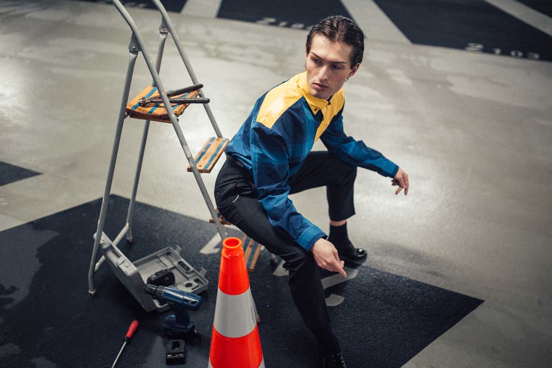 Matthew in blau gelben Hemd sitzt auf einer Leiter und denkt über die Relevanz der Mode nach.
