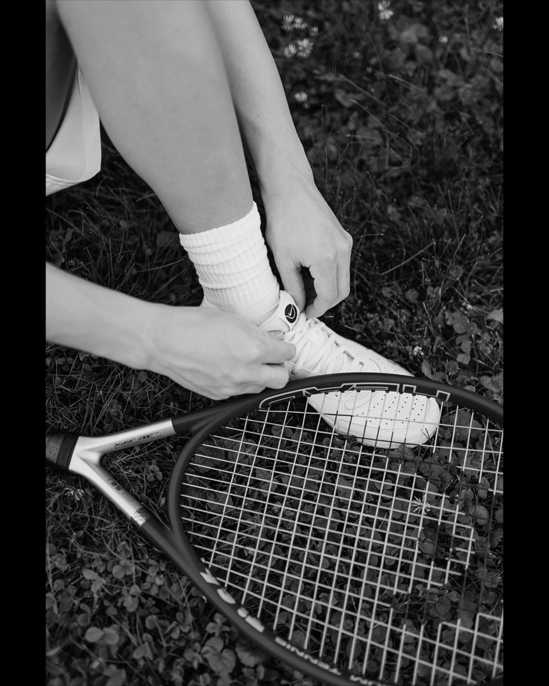 Weiße Sneaker für Tennis von Nike und schwarzer Tennisschläger von Headtennis.